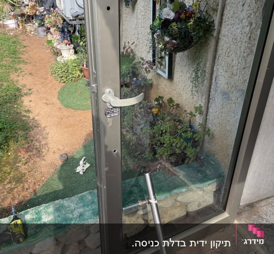 דלת זכוכית עם ידית מתכת פתוחה בחצר